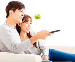 happy young couple watching tv in living room