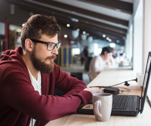 Young man in glasses sitting and using laptop