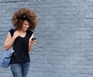 Smiling woman walking and looking at mobile phone