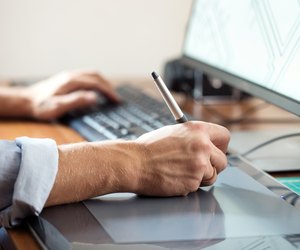 Graphic designer using digital tablet and computer in office or