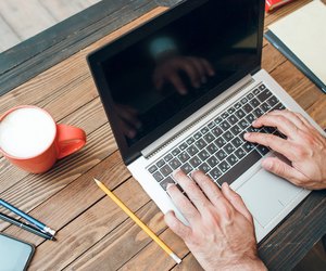 Male hands typing on laptop keyboard, mockup