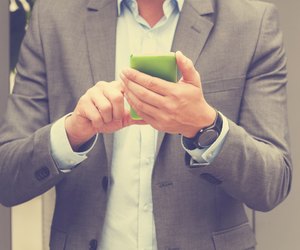 Elegant man using cellphone outdoors.