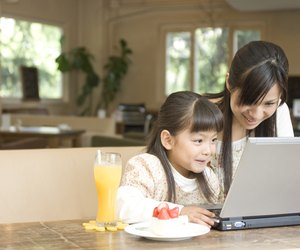 Mother and daughter using laptop at a cafe