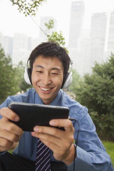 Young businessman listening to music on his MP4 player
