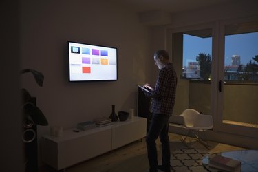 Senior man using smart TV apps on digital tablet in dark living room