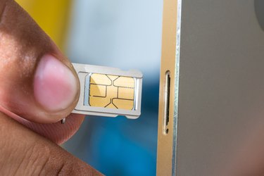 Cropped Image Of Hand Inserting Sim Card In Mobile Phone