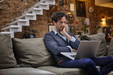 Man using laptop on couch at home