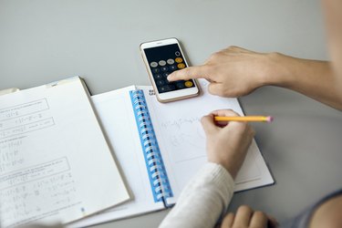 Students using smartphone calculator function while completing math assignment