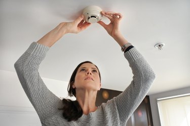 Woman checking smoke detector