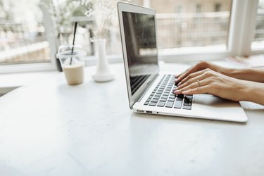 European hands typing on laptop keyabord on white table