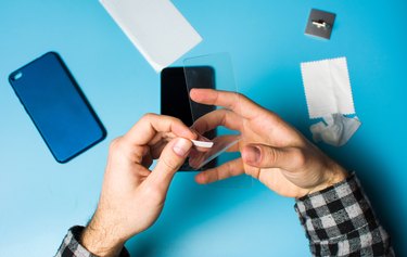 Man applying protective tempered glass to phone screen