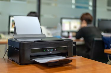 black printer in office with soft-focus and over light in the background