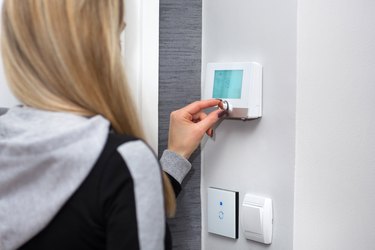 Girl adjusts and regulate the room temperature on smart switch