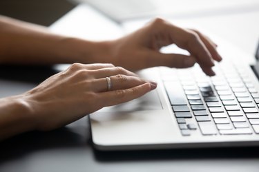 Close up female hands typing on laptop keyboard