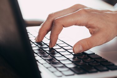 Woman using laptop on light table, closeup