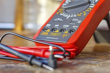 Digital multimeter with probes on a wooden table in the workshop