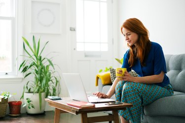 Woman using laptop from sofa