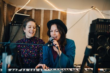 Performers playing piano and singing while practicing in studio