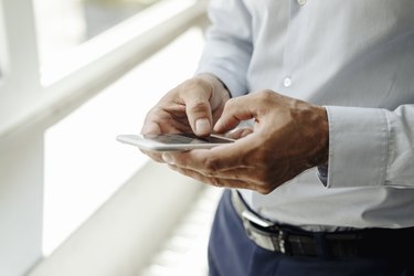 Close-up of businessman at the window using cell phone