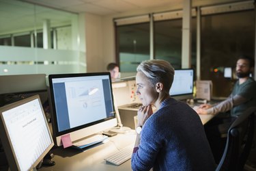 Businesswoman working late at computers in office