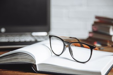 Eyeglasses on an open notebook on a wooden background.