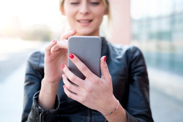 Young girl texting and using smart phone in the city