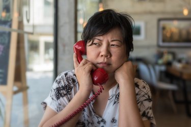 Serious Woman Talking On Telephone At Home