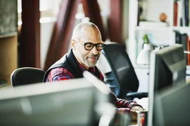 Businessman looking at computer monitor at workstation in design office