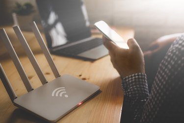 closeup of a wireless router and a man using smartphone on living room at home ofiice