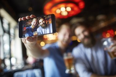 Male friends in the bar posing for a selfie