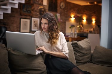 Woman using laptop on couch at home