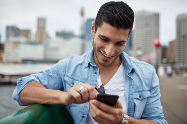 Young millennial man using smart phone in city