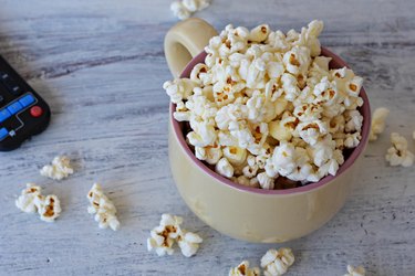 A bowl of delicious caramel popcorn on a white wooden background