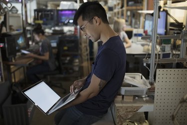 Male engineer working at laptop in workshop