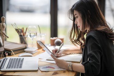 female designer working with paperwork  and looking at tablet screen