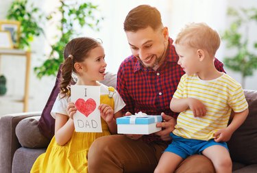 Happy father's day! Children congratulates dad and gives him gift and postcard