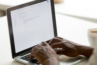 African american businessman typing e-mail on laptop using online application