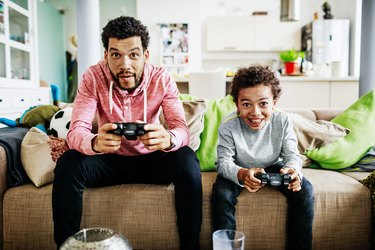 Father And Son Concentrating While Playing Video Games Together