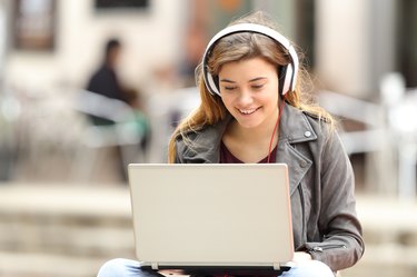 Girl listening and downloading music from laptop