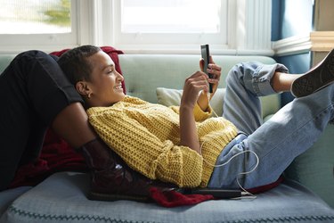 Woman messaging on phone while leaning on friend