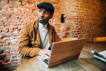 Young man sitting in coffee shop and using laptop