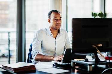 Office Manager Working On Computer At His Desk