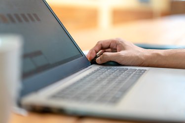 Close up asian man's hand and finger work on his laptop with coffee cup foreground and wood environment furniture."n"n