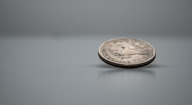 US Dollar Coin on Edge, Spinning, White Background, Frozen in Motion