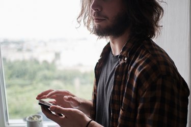 Young bearded man using phone at home