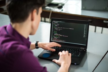 Young man using his laptop to try to solve problem with code