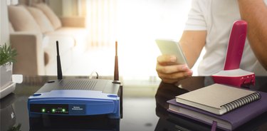 closeup of a wireless router and a young man using smart phone on living room at home