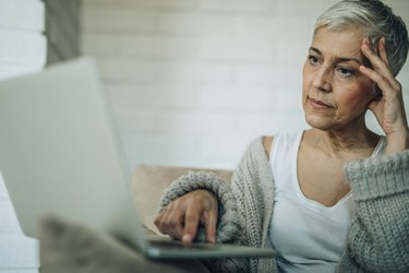 Worried senior woman reading an e-mail on laptop.