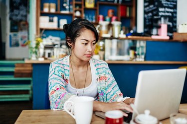 Young Woman Working On Laptop In Colourful Coffee Shop