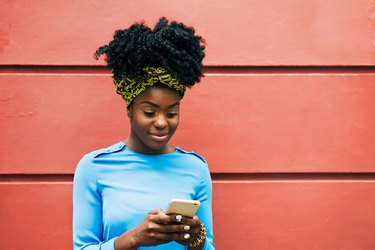 Woman using smart phone infront of wall